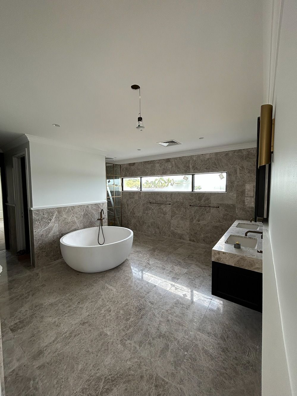 Renovated main bathroom with stone tiling, freestanding bath and brass tapware